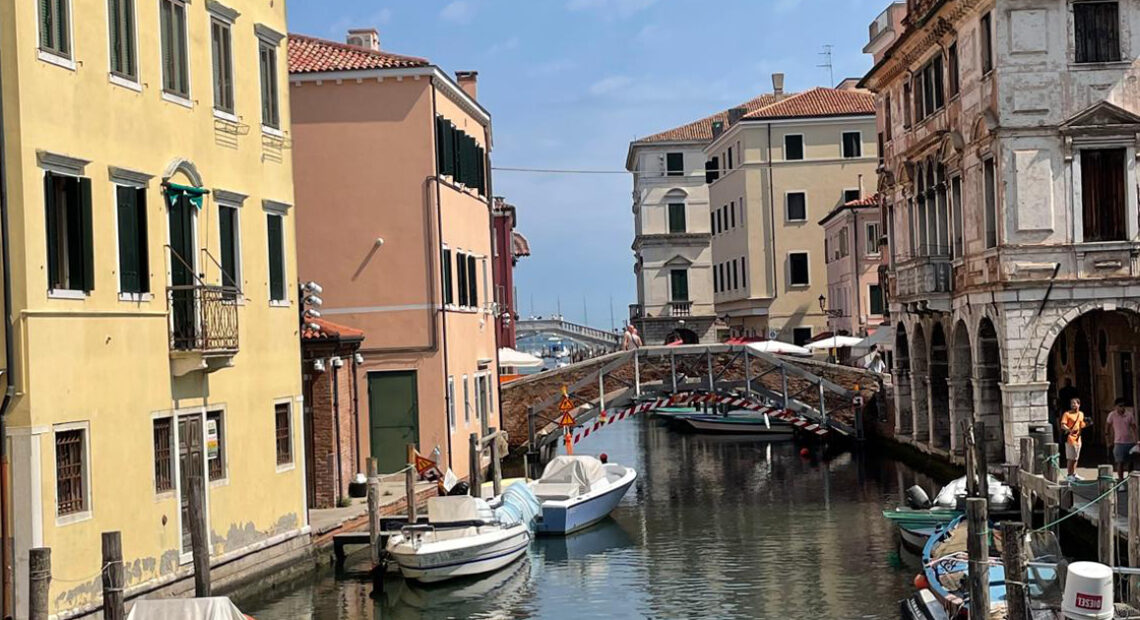 Scorcio suggestivo di un canale interno di Chioggia, la Piccola Venezia, con le tipiche imbarcazioni ormeggiate e i palazzi storici che si riflettono nell'acqua.