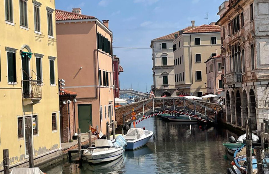 Scorcio suggestivo di un canale interno di Chioggia, la Piccola Venezia, con le tipiche imbarcazioni ormeggiate e i palazzi storici che si riflettono nell'acqua.