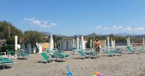 Spiaggia di Marinella con ombrelloni chiusi e attrezzature balneari da allestire