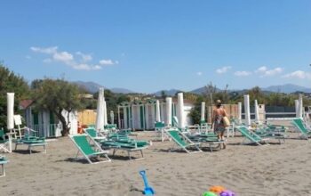 Spiaggia di Marinella con ombrelloni chiusi e attrezzature balneari da allestire