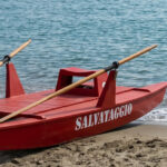 Un pattino di salvataggio rosso sulla sabbia in riva al mare aperto