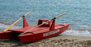 Un pattino di salvataggio rosso sulla sabbia in riva al mare aperto