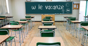 Banchi di scuola vuoti e lavagna con la scritta Viva le vacanze