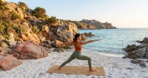 Una persona pratica yoga sulla spiaggia al mattino davanti al mare.