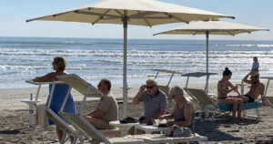 Turisti e bagnanti si rilassano sotto gli ombrelloni in uno stabilimento gestito dai balneari di Riccione.