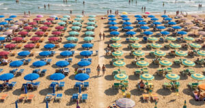 Stabilimento balneare della Riviera romagnola con file di ombrelloni e lettini rivolti verso il mare aperto