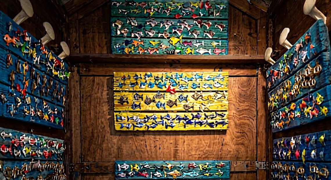 Interno di una cabina balneare in legno decorata con pannelli colorati pieni di pesciolini artistici in ceramica per la mostra Una Cabina d'Artista.