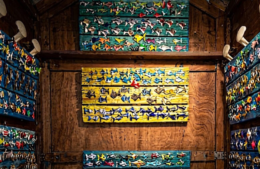 Interno di una cabina balneare in legno decorata con pannelli colorati pieni di pesciolini artistici in ceramica per la mostra Una Cabina d'Artista.