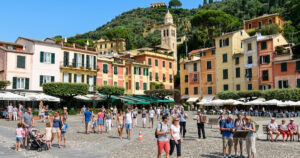 La celebre piazzetta di Portofino affollata di turisti con le tipiche case colorate e la chiesa di San Giorgio sullo sfondo.