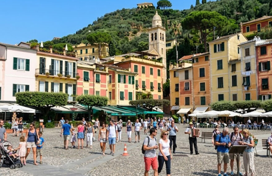 La celebre piazzetta di Portofino affollata di turisti con le tipiche case colorate e la chiesa di San Giorgio sullo sfondo.
