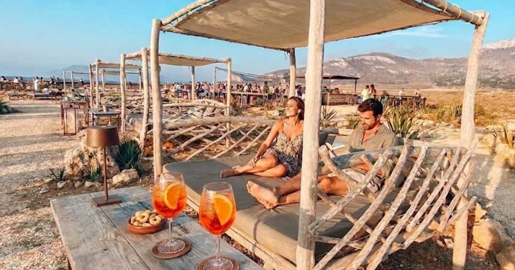 Coppia che fa un aperitivo al tramonto in un gazebo alla Baia del Faro a Favignana