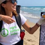 Due donne promuovono il riciclo delle lattine in alluminio su una spiaggia attrezzata