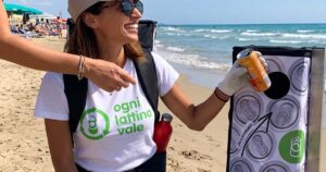 Due donne promuovono il riciclo delle lattine in alluminio su una spiaggia attrezzata