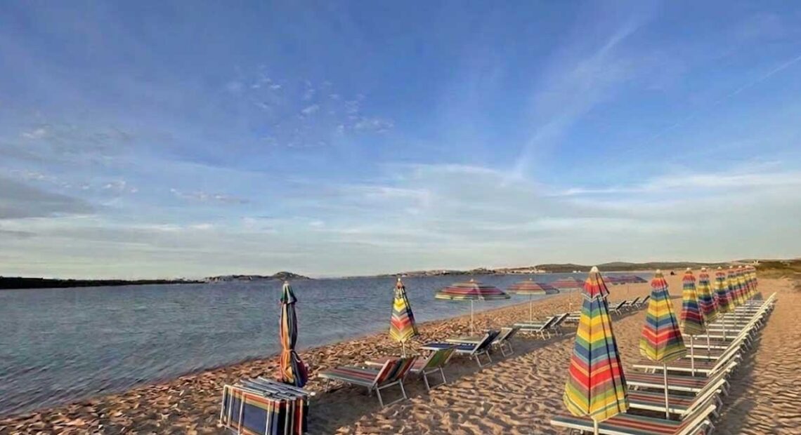 Fila di ombrelloni e lettini sulla sabbia in una spiaggia della Sardegna