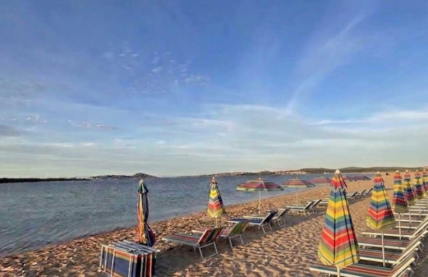 Fila di ombrelloni e lettini sulla sabbia in una spiaggia della Sardegna