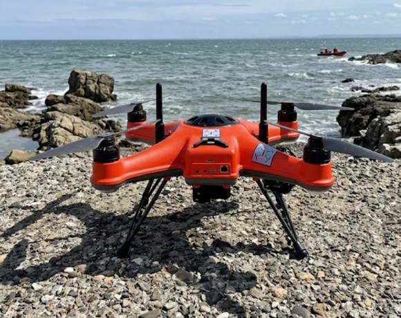 Drone di salvataggio arancione posizionato sulla costa prima dell'intervento in mare.