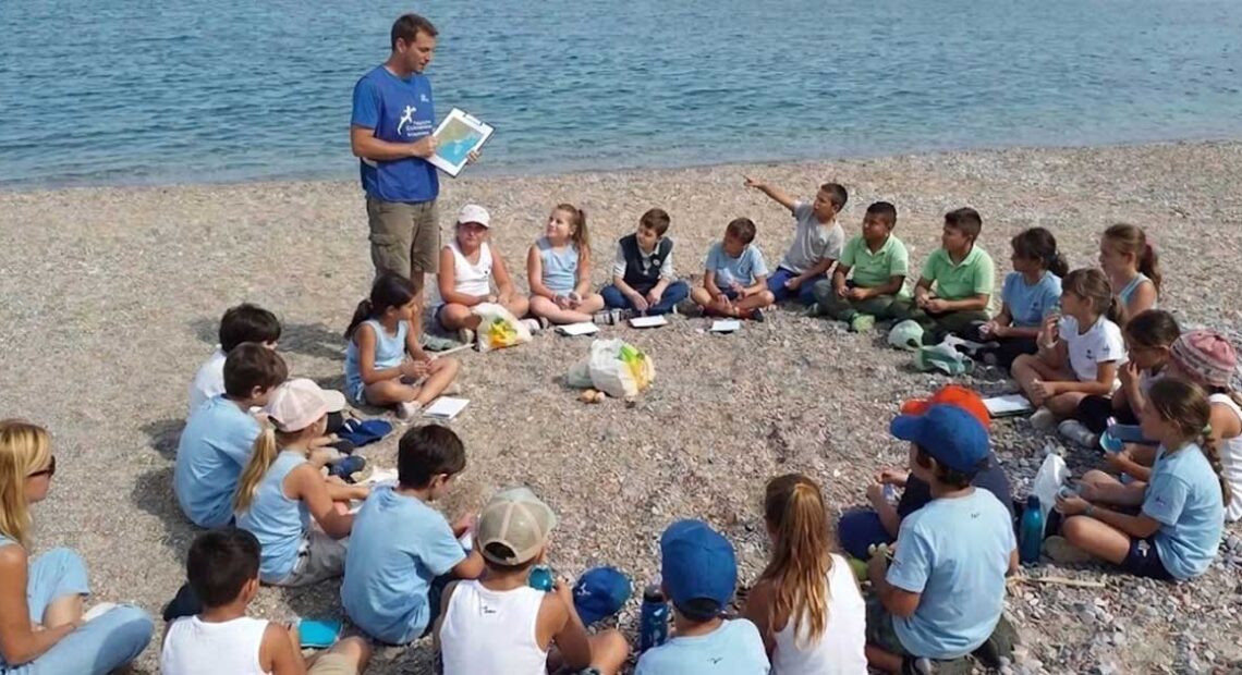 bambini seduti in cerchio sulla spiaggia per un'attivita di educazione ambientale