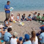 bambini seduti in cerchio sulla spiaggia per un'attivita di educazione ambientale