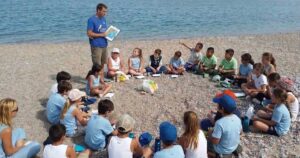 bambini seduti in cerchio sulla spiaggia per un'attivita di educazione ambientale