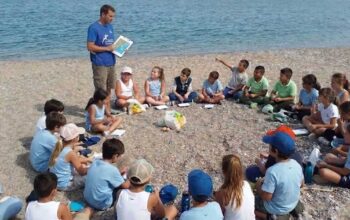 bambini seduti in cerchio sulla spiaggia per un'attivita di educazione ambientale