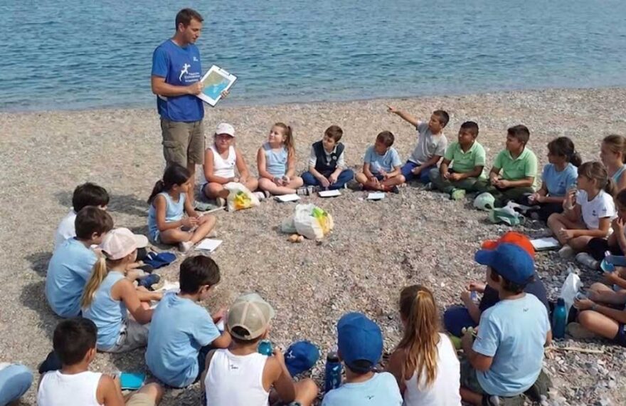 bambini seduti in cerchio sulla spiaggia per un'attivita di educazione ambientale