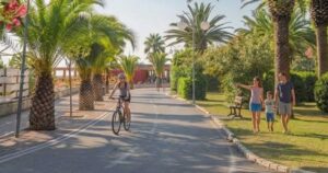 Vista del lungomare di Tortoreto Lido con pista ciclabile, palme, una ciclista e una famiglia a passeggio.