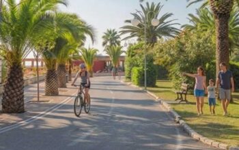 Vista del lungomare di Tortoreto Lido con pista ciclabile, palme, una ciclista e una famiglia a passeggio.