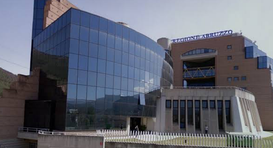Facciata del Palazzo della Regione Abruzzo a L'Aquila, con insegna blu e struttura a tralicci gialli