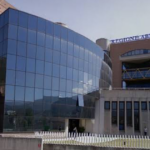 Facciata del Palazzo della Regione Abruzzo a L'Aquila, con insegna blu e struttura a tralicci gialli