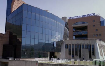 Facciata del Palazzo della Regione Abruzzo a L'Aquila, con insegna blu e struttura a tralicci gialli
