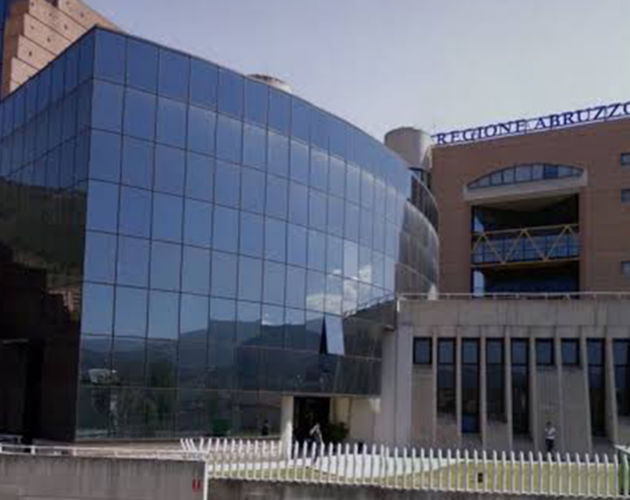 Facciata del Palazzo della Regione Abruzzo a L'Aquila, con insegna blu e struttura a tralicci gialli