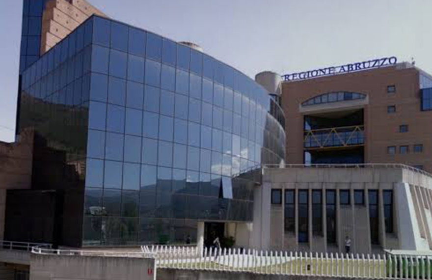 Facciata del Palazzo della Regione Abruzzo a L'Aquila, con insegna blu e struttura a tralicci gialli