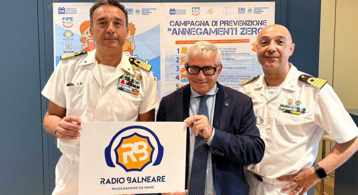 Antonio Capacchione presidente SIB con ufficiali della Guardia Costiera mostra il logo di Radio Balneare alla presentazione della campagna Annegamenti Zero.