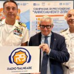 Antonio Capacchione presidente SIB con ufficiali della Guardia Costiera mostra il logo di Radio Balneare alla presentazione della campagna Annegamenti Zero.