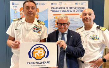 Antonio Capacchione presidente SIB con ufficiali della Guardia Costiera mostra il logo di Radio Balneare alla presentazione della campagna Annegamenti Zero.