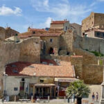 La maestosa Rocca Aldobrandesca e le mura storiche di Giglio Castello sotto un cielo azzurro con nuvole bianche