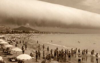 Spettacolare nuvola a rullo (Roll Cloud) cilindrica sulla spiaggia di Hendaye in Francia, con bagnanti che guardano il cielo.