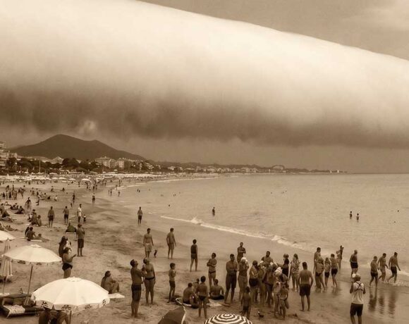 Spettacolare nuvola a rullo (Roll Cloud) cilindrica sulla spiaggia di Hendaye in Francia, con bagnanti che guardano il cielo.