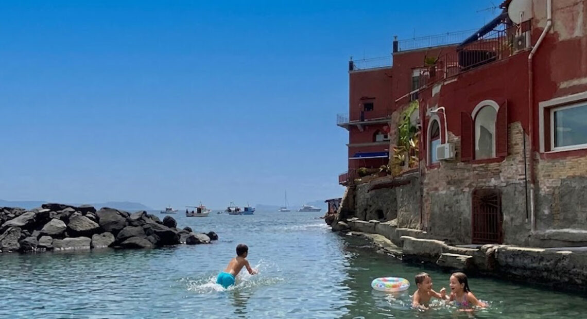 Bagnanti in mare alla spiaggia delle Monache a Posillipo senza servizi balneari attivi