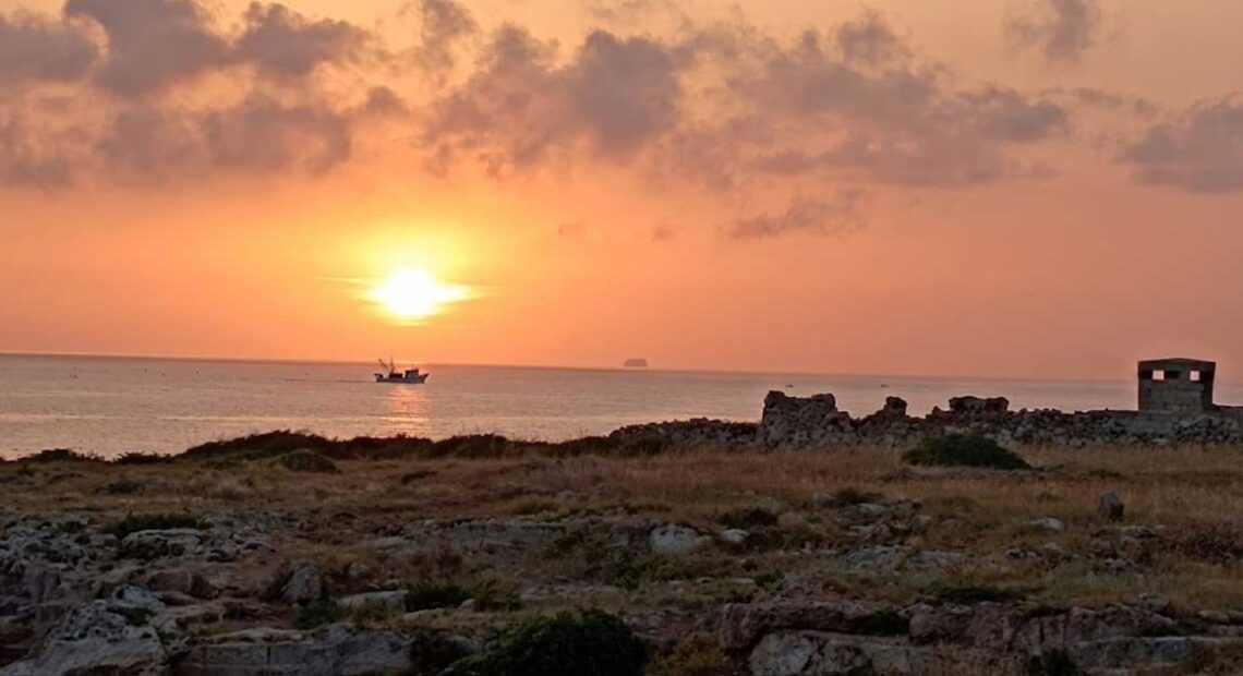 Alba sul mare a Torre Incina lungo la costa tra Polignano e Monopoli con peschereccio al largo.