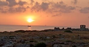 Alba sul mare a Torre Incina lungo la costa tra Polignano e Monopoli con peschereccio al largo.