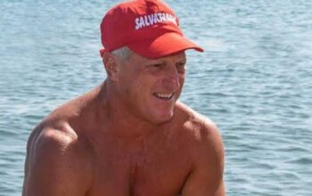 Un torretta di salvataggio con la boa rossa in spiaggia di fronte al mare mosso.