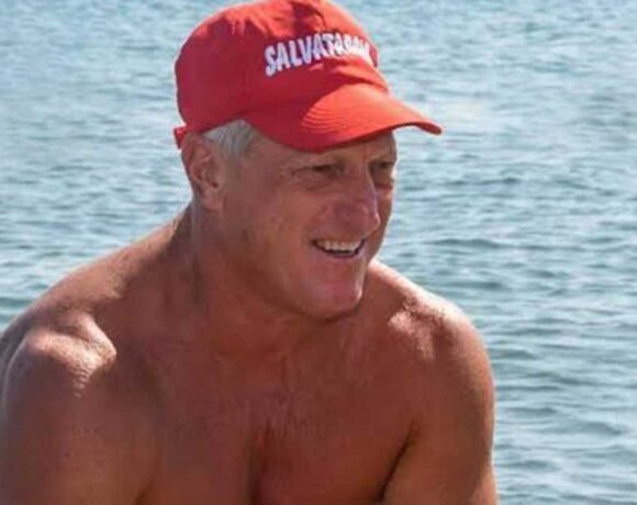 Un torretta di salvataggio con la boa rossa in spiaggia di fronte al mare mosso.