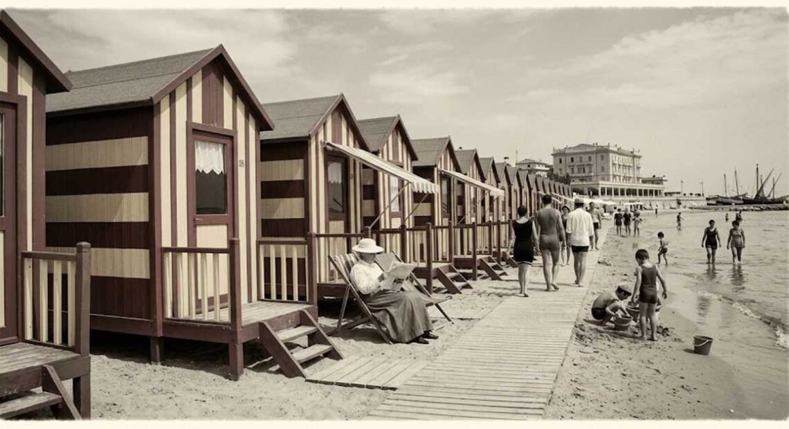 Ricostruzione d'epoca di una fila di cabine balneari in legno a righe sulla spiaggia con bagnanti nei primi del Novecento.