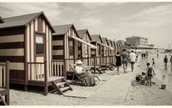 Ricostruzione d'epoca di una fila di cabine balneari in legno a righe sulla spiaggia con bagnanti nei primi del Novecento.