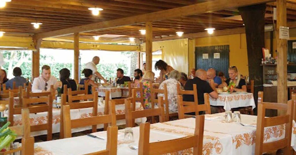 Sala esterna del ristorante Casa delle Aie a Cervia con tavoli apparecchiati e clienti a cena.