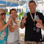 Un gruppo di persone brinda con calici di vino durante un'iniziativa di degustazione in spiaggia a Cattolica.