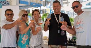 Un gruppo di persone brinda con calici di vino durante un'iniziativa di degustazione in spiaggia a Cattolica.