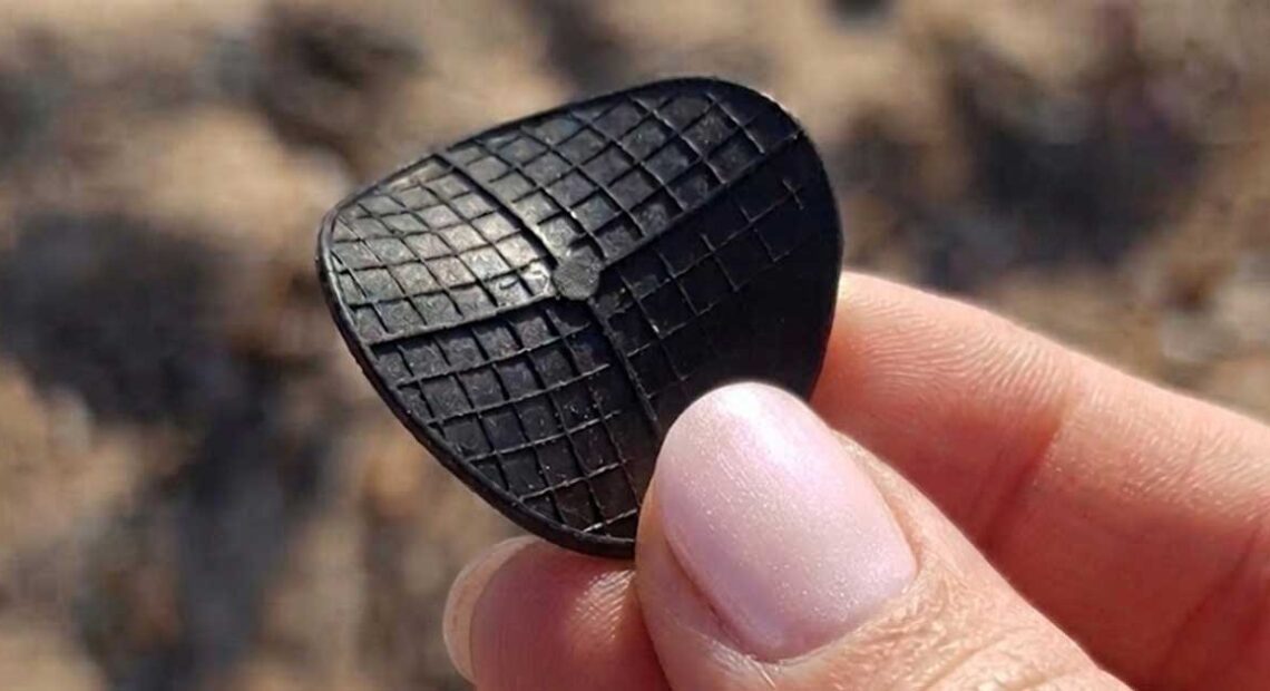 Dettaglio di un dischetto nero di plastica tipo carrier per depuratori ritrovato in spiaggia.