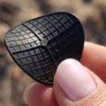Dettaglio di un dischetto nero di plastica tipo carrier per depuratori ritrovato in spiaggia.